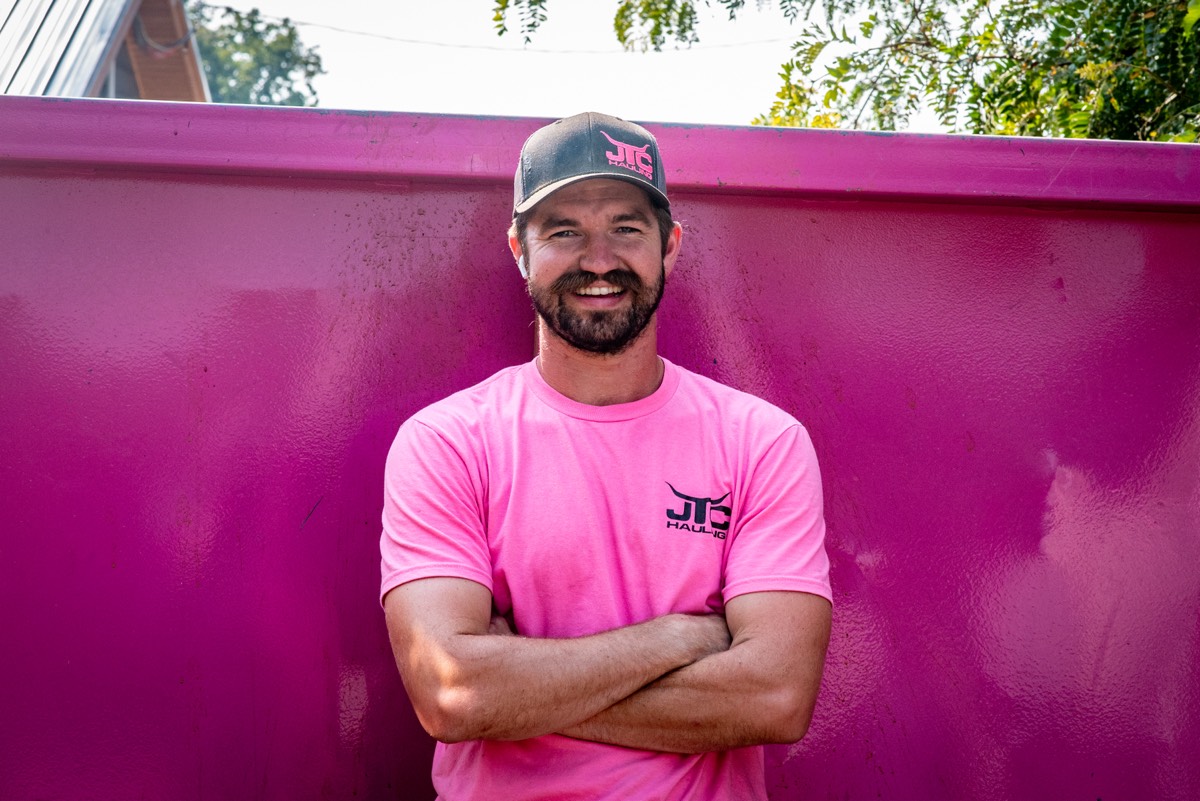 Jared Cozzocrea, owner of JTC Demolition, standing in front of a pink JTC dumpster