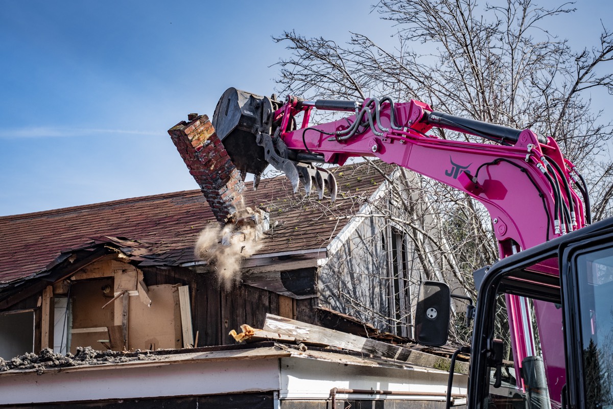 Close-up of JTC excavator carefully taking apart a roof during deconstruction
